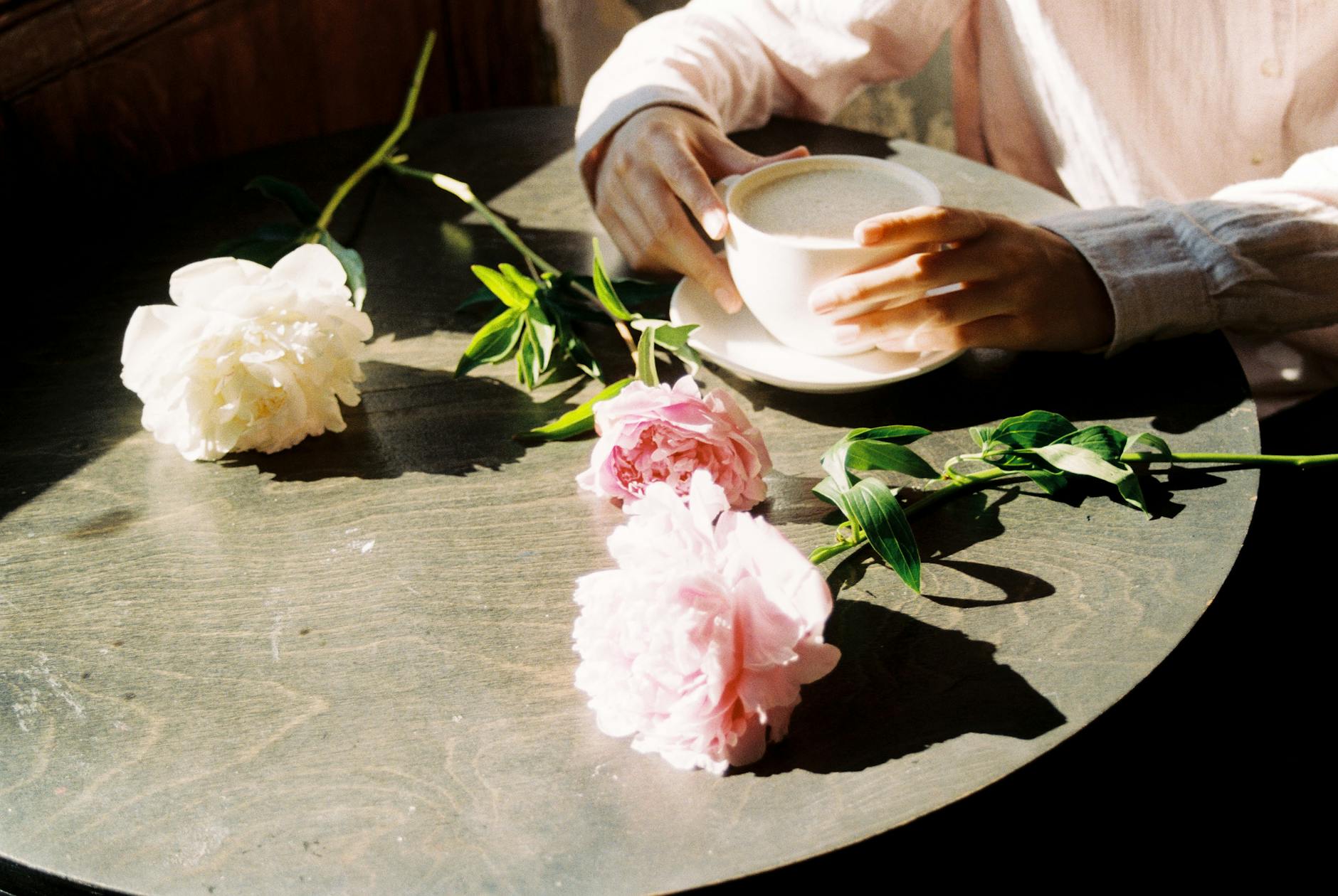 Kubek kawy i piwonie na stole w porannym, ciepłym świetle