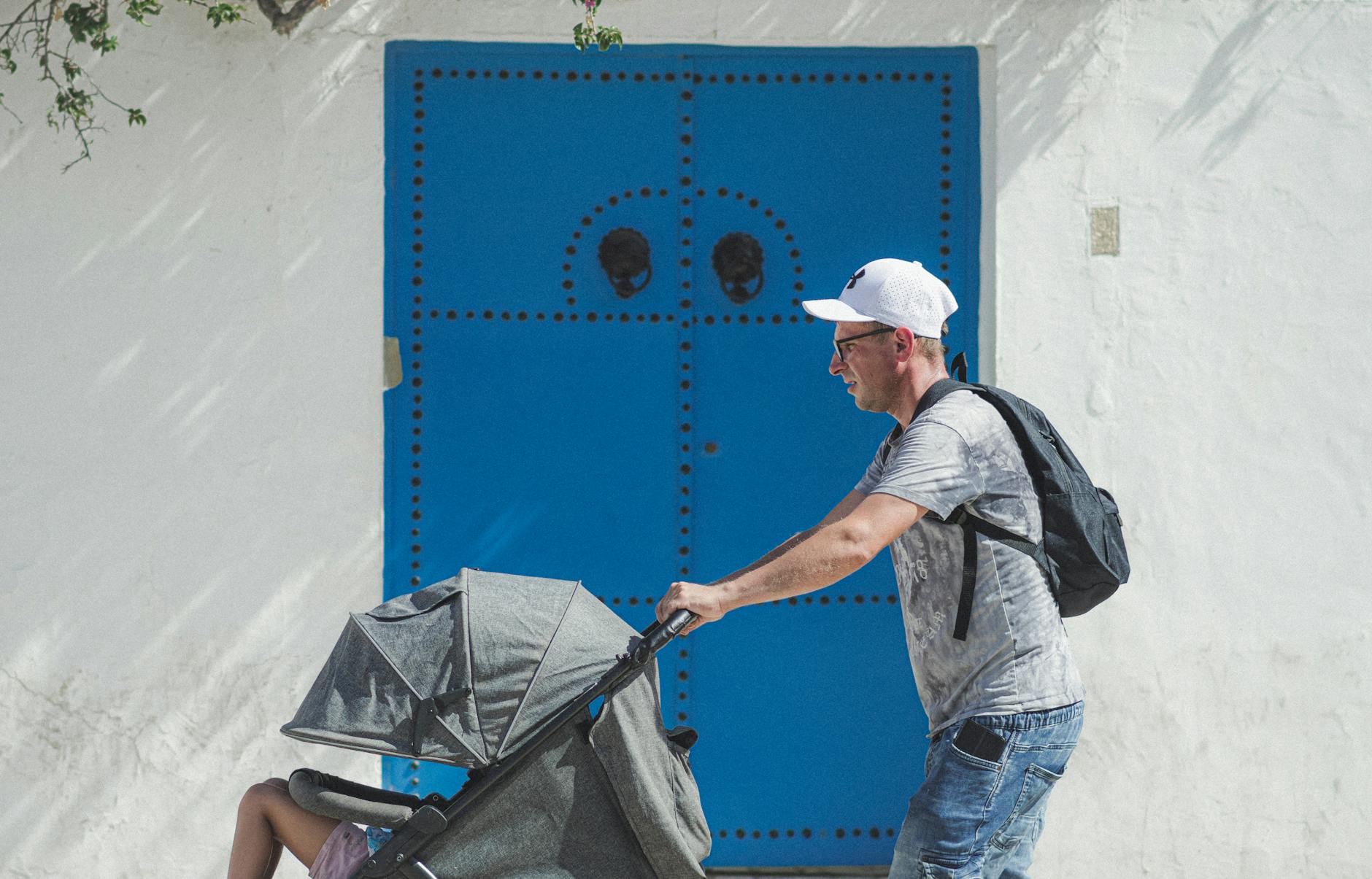 Ojciec z wózkiem przy tradycyjnych niebieskich drzwiach w Kartaginie