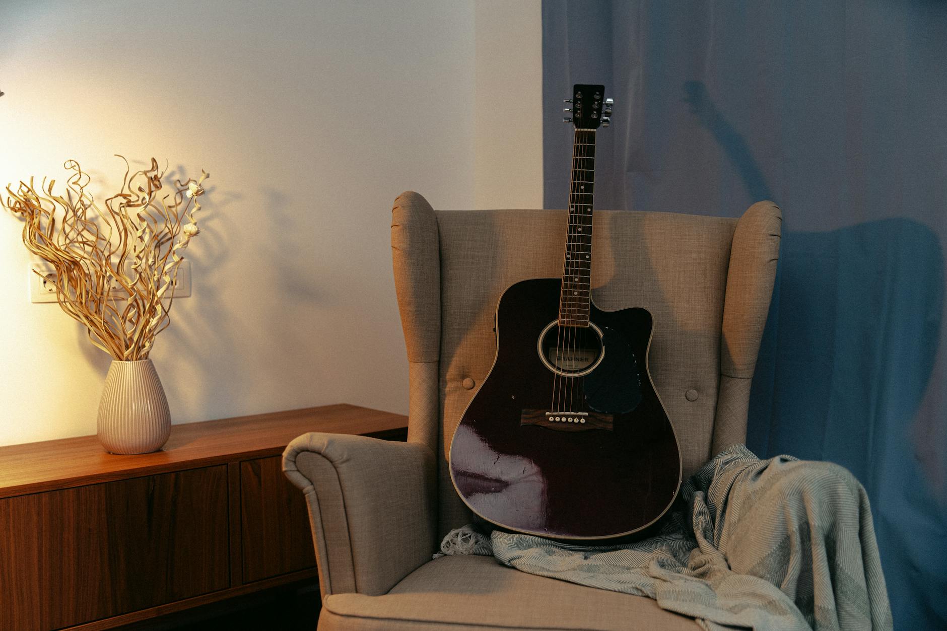 Gitara akustyczna na fotelu w przytulnym, ciepło oświetlonym salonie