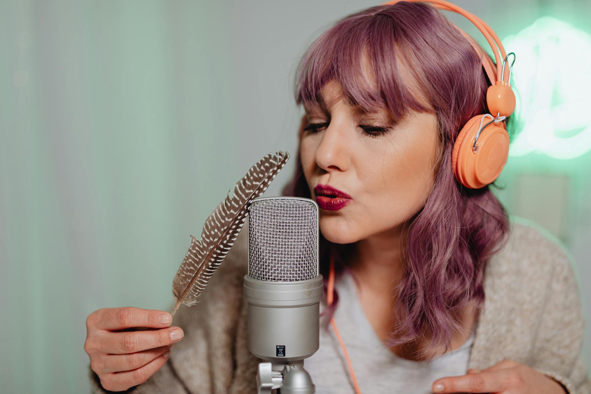 Kobieta tworząca dźwięki ASMR piórkiem przy mikrofonie