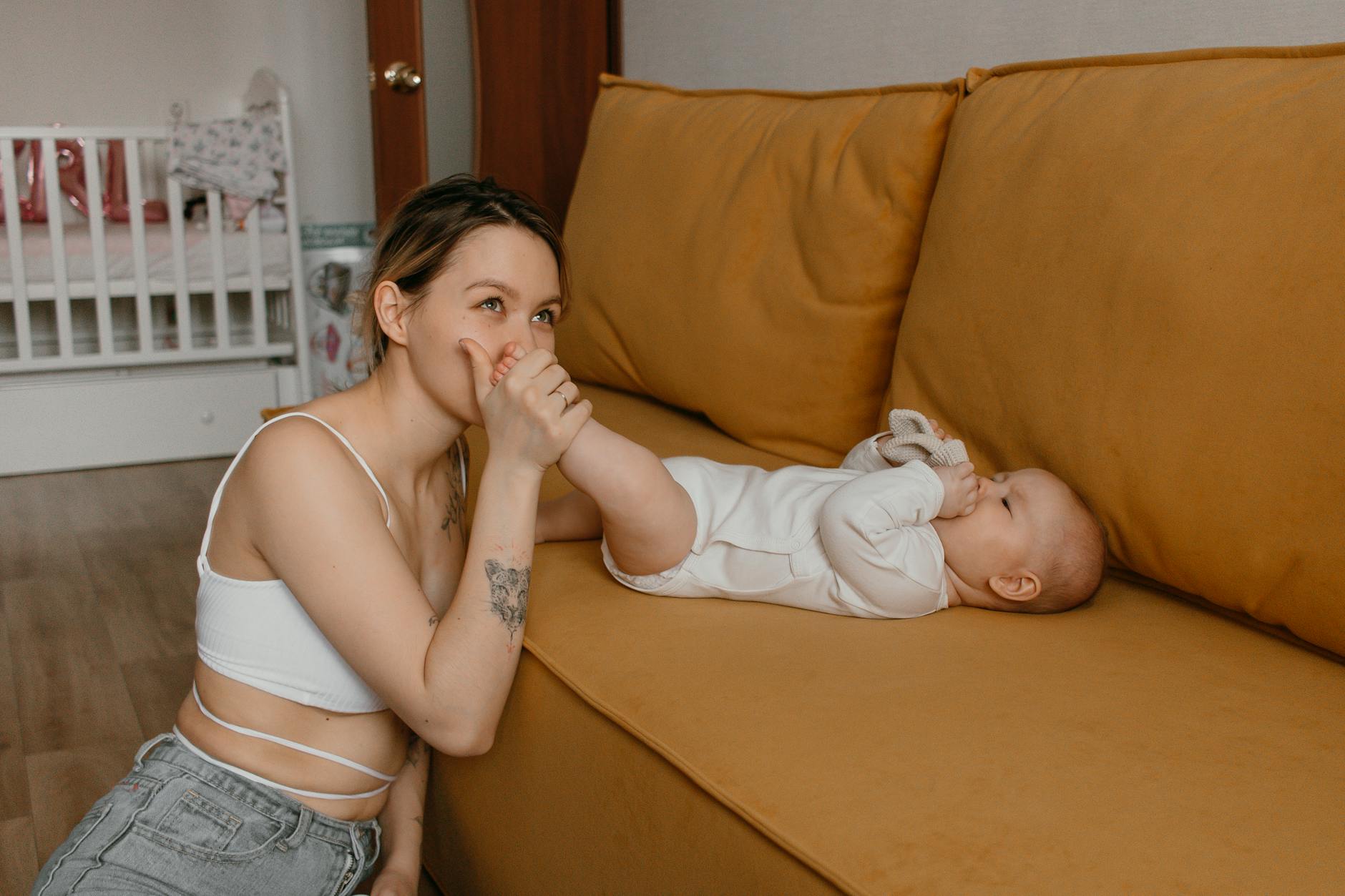 Mama przytula niemowlę na kanapie w przytulnym domu