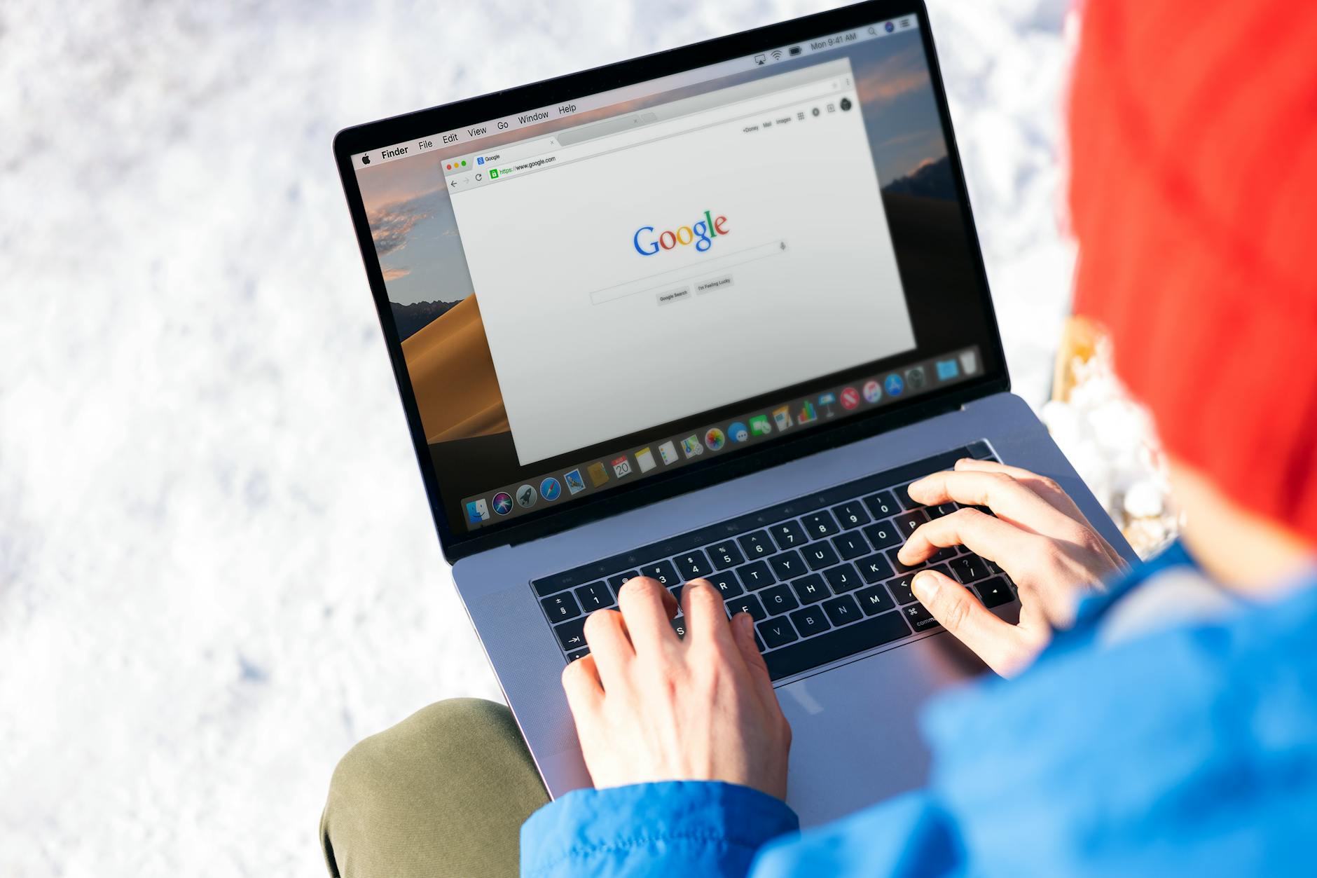Osoba pisze na laptopie na śniegu, korzystając z internetu