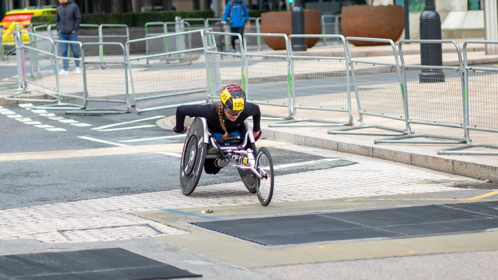 Zawodnik na wózku wyścigowym jedzie ulicami miasta podczas maratonu