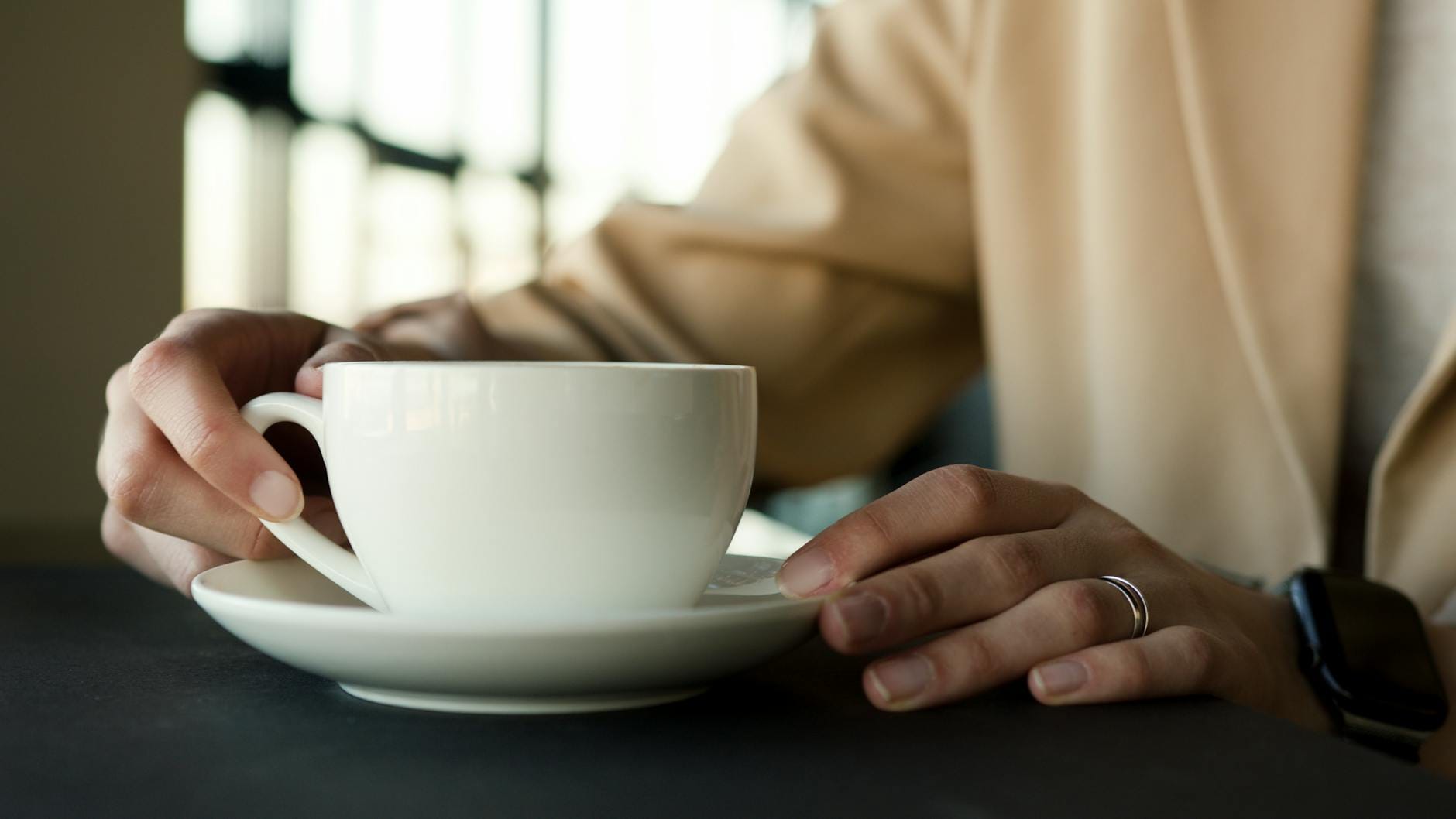 Zbliżenie na kobietę trzymającą porcelanową filiżankę kawy w domu