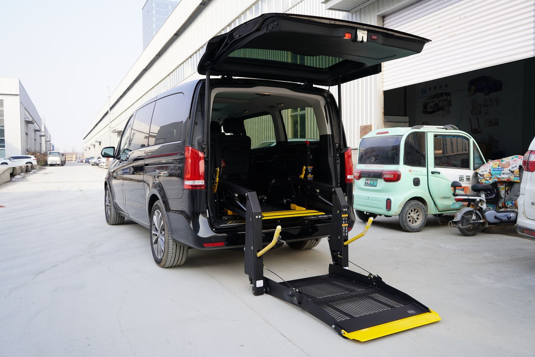 Czarny van z windą hydrauliczną dla wózka inwalidzkiego na ulicy
