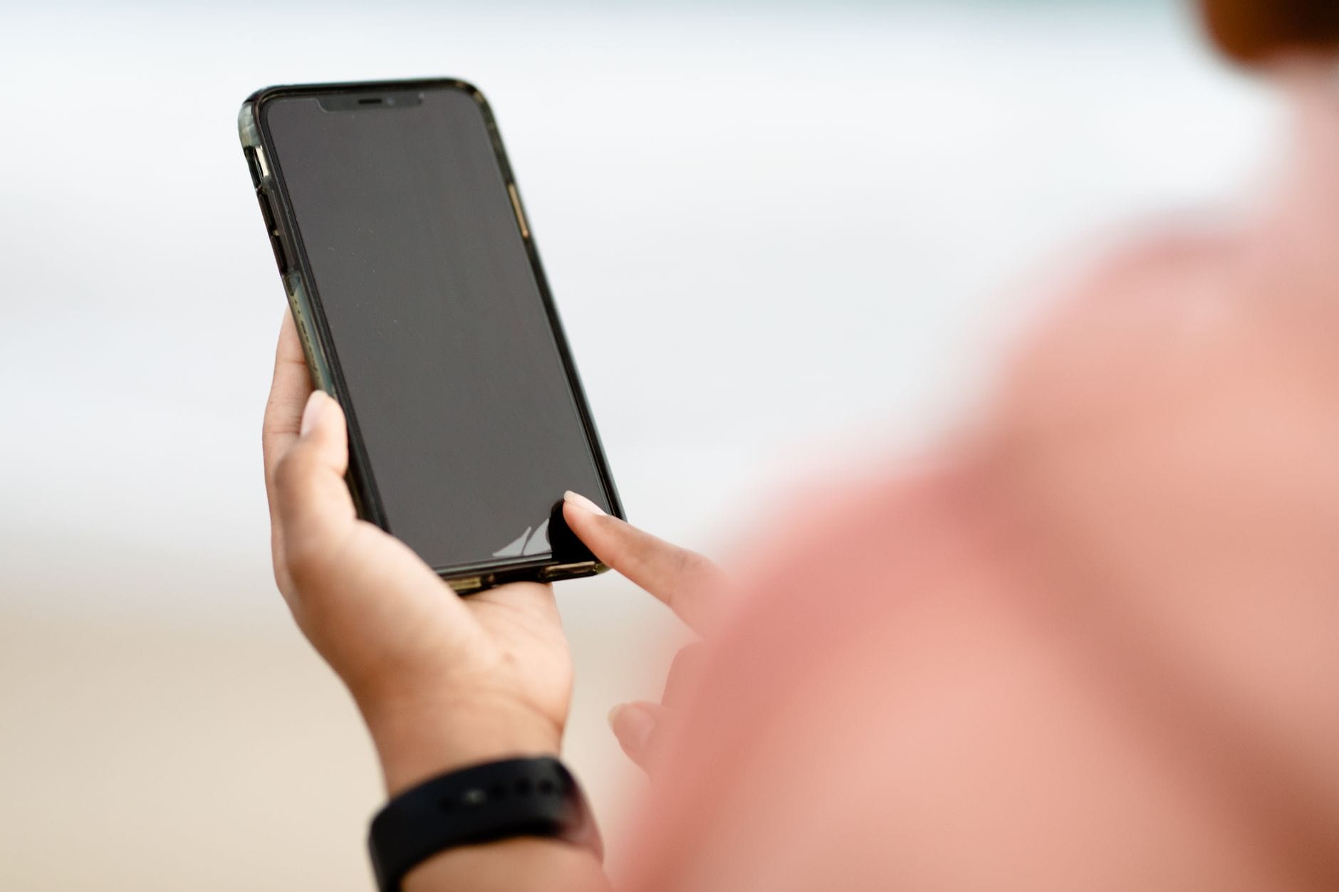 Dłoń obsługująca ekran smartfona na zewnątrz