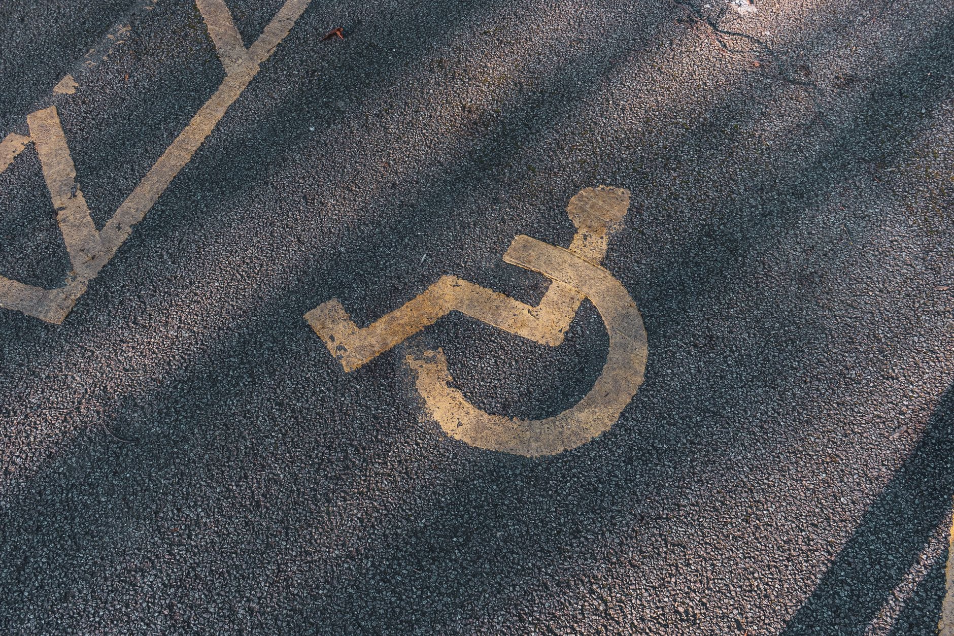 Miejsce parkingowe na asfalcie z żółtym symbolem wózka inwalidzkiego