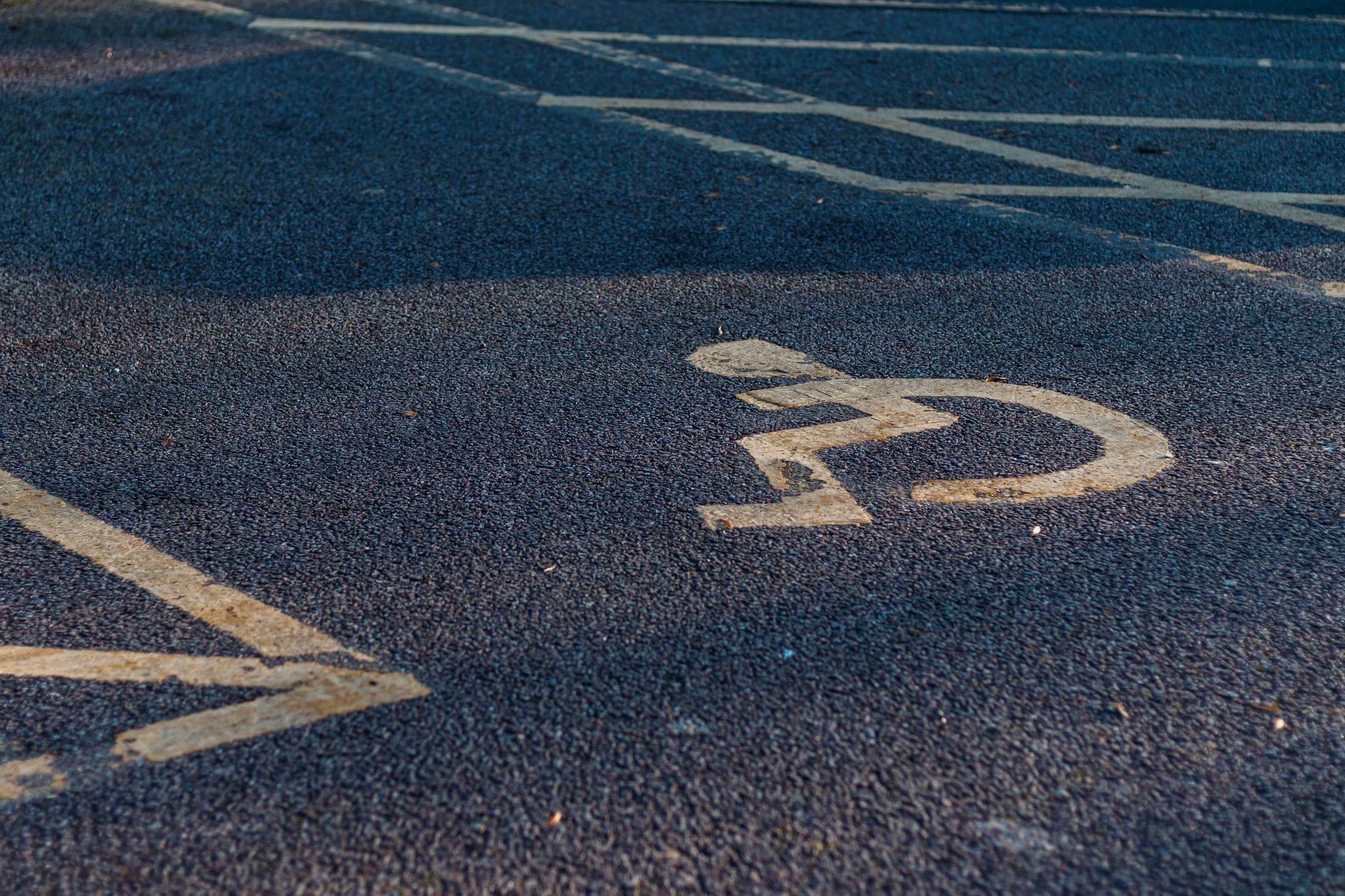 Żółty symbol wózka inwalidzkiego namalowany na asfalcie parkingu