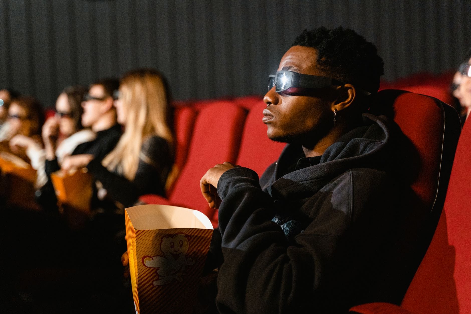 Dorośli w kinie w okularach 3D oglądają film i jedzą popcorn