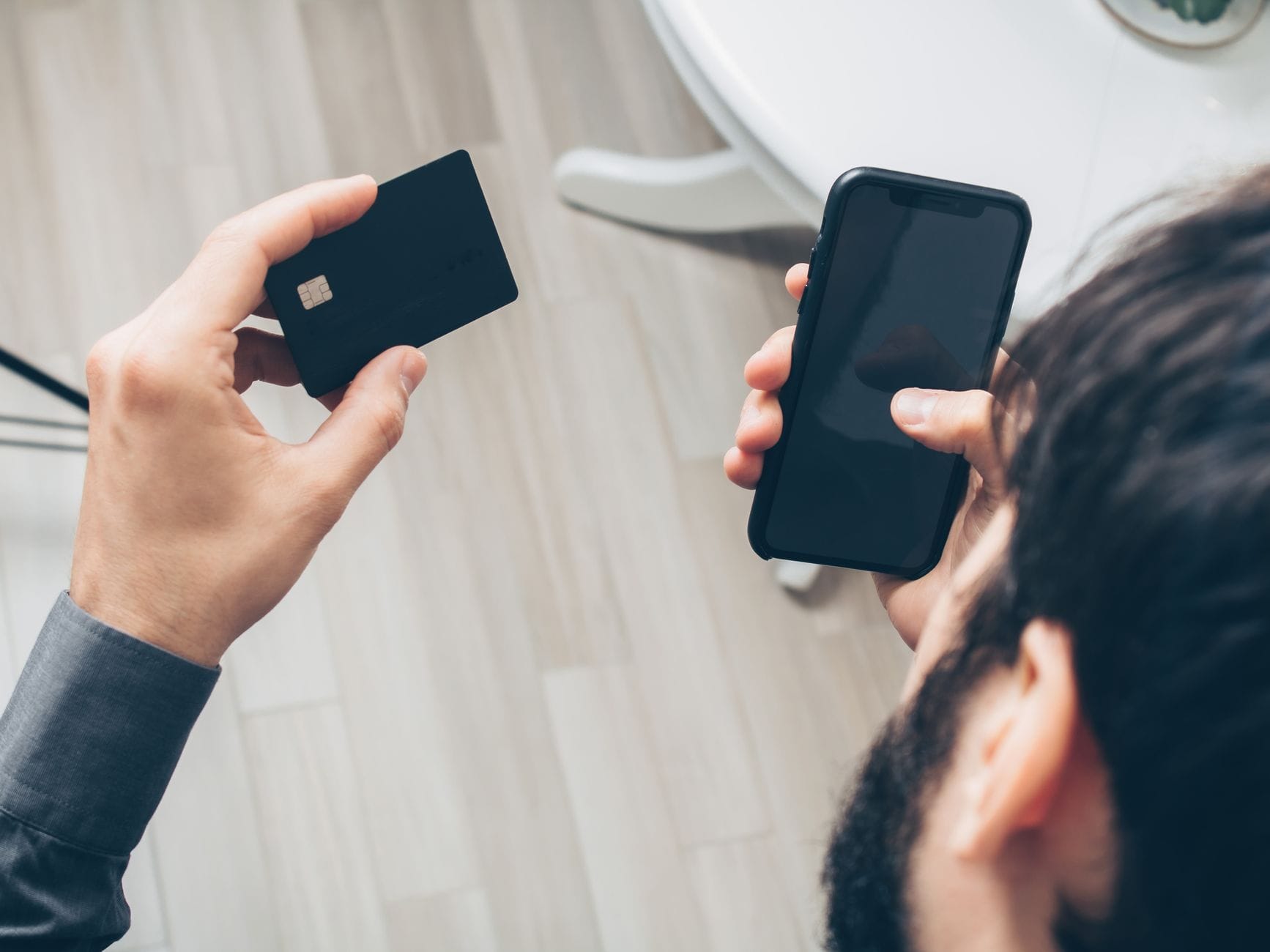 Mężczyzna trzymający smartfon i kartę podczas płatności online