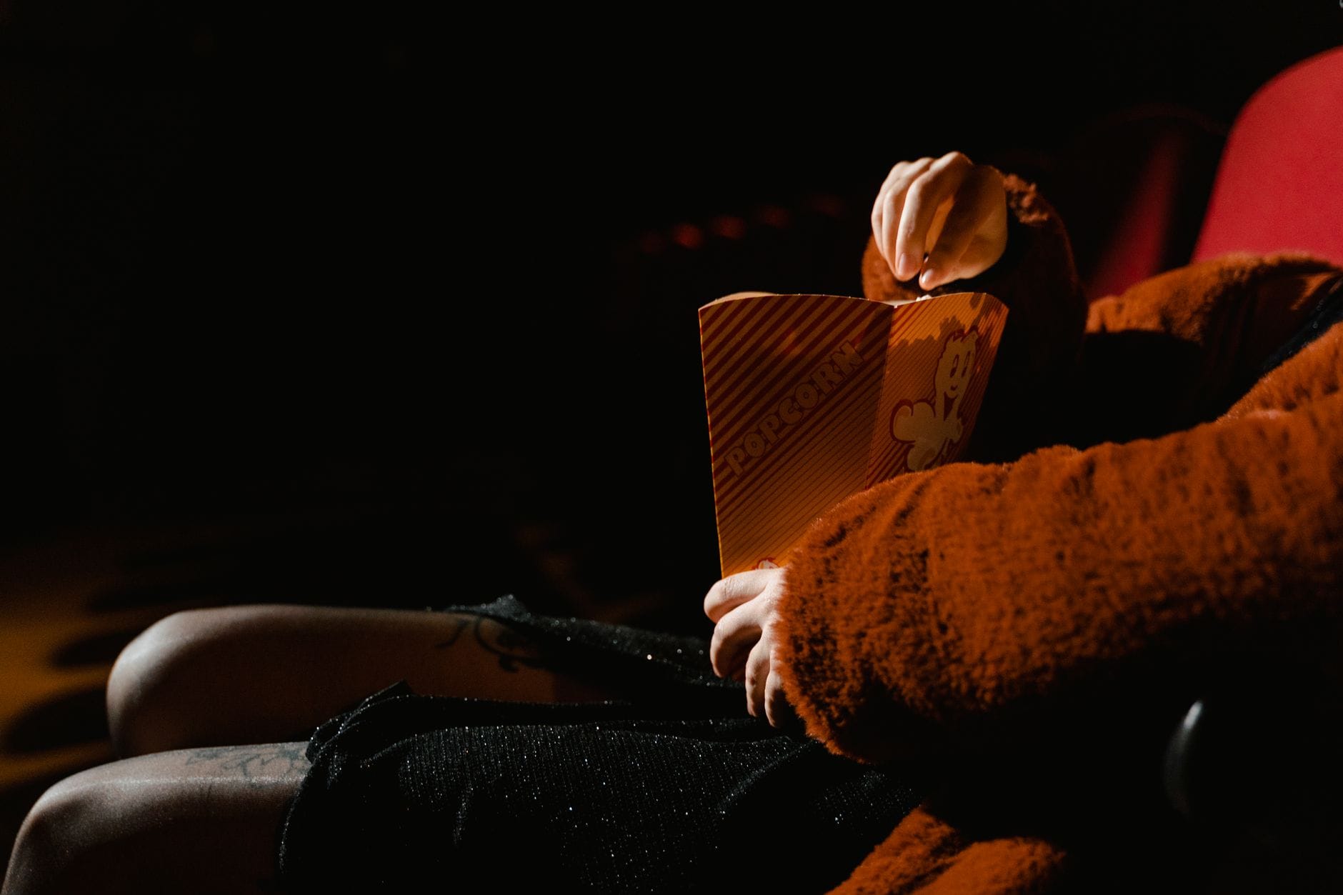 Osoba z popcornem ogląda film w sali kinowej Osoba z popcornem ogląda film w sali kinowej