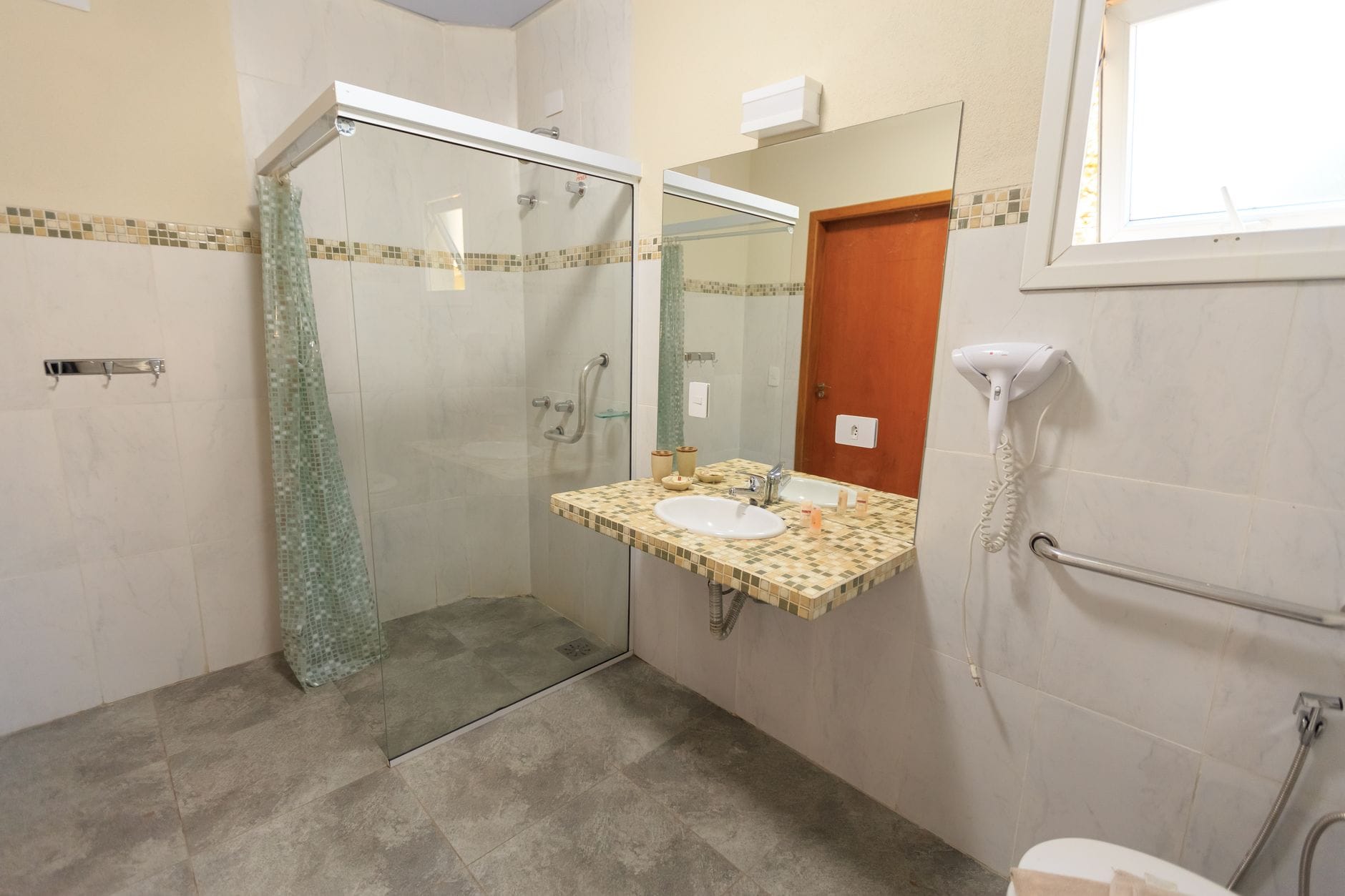 Przestronna, bezprogowa łazienka hotelowa z dużym prysznicem i umywalką