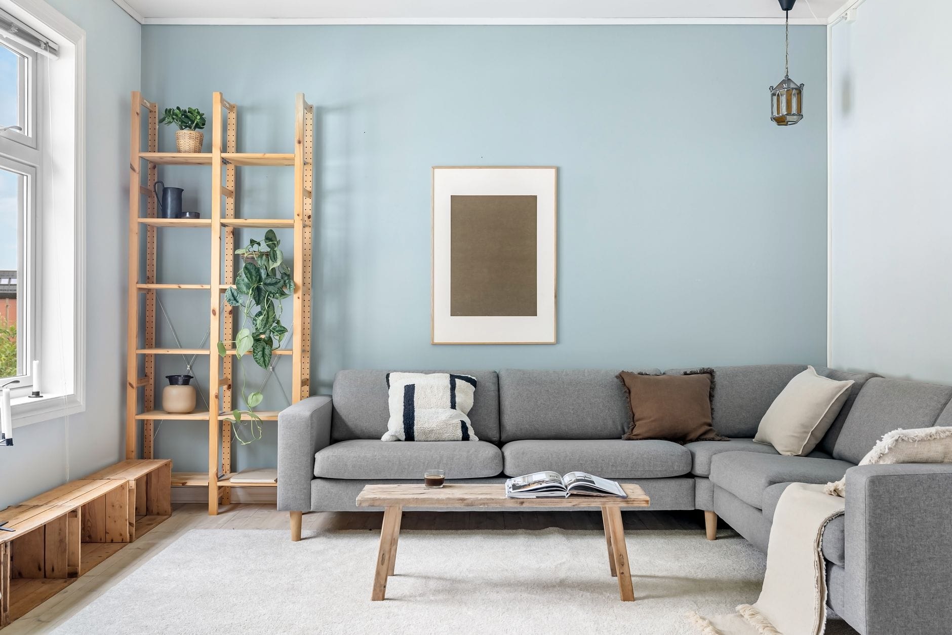 Skandynawski salon z szarą sofą i drewnianymi dodatkami