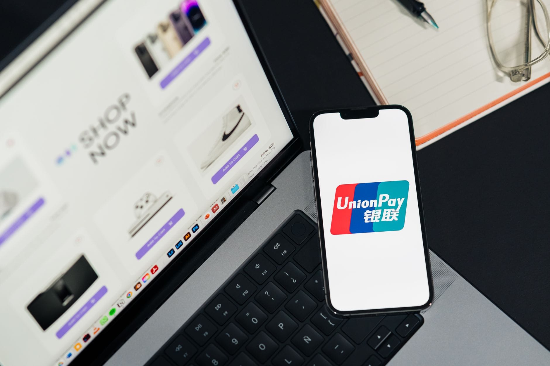 Smartfon z logo UnionPay obok laptopa z otwartą stroną sklepu online