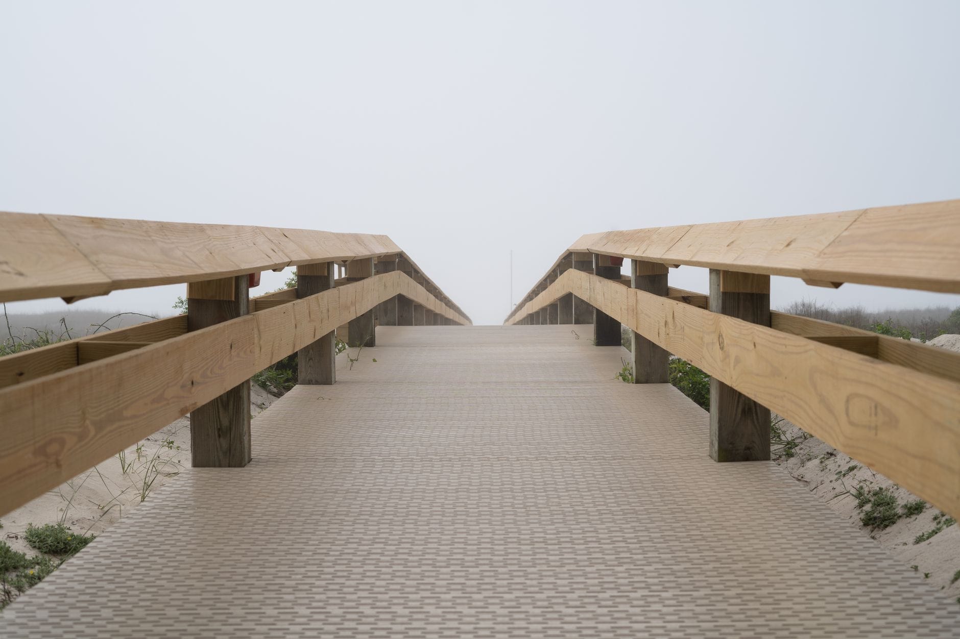 Drewniany pomost prowadzący na mglistą, pustą plażę
