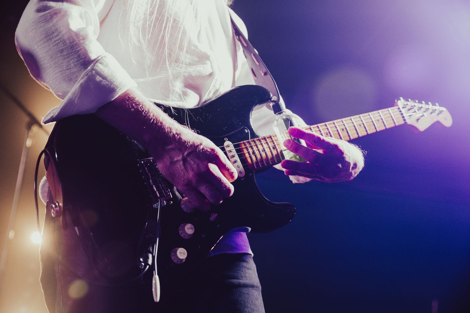 Gitarzysta rockowy grający z pasją na scenie w kolorowych światłach