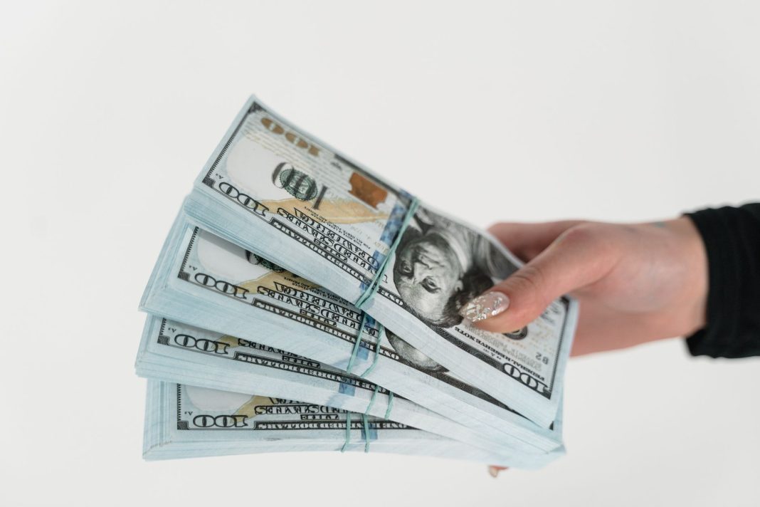 Stosy banknotów dolarowych trzymane w dłoni na białym Stosy banknotów dolarowych trzymane w dłoni na białym