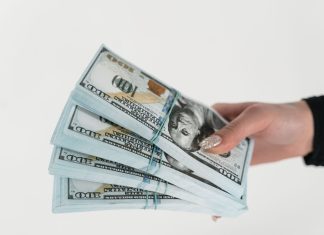 Stosy banknotów dolarowych trzymane w dłoni na białym